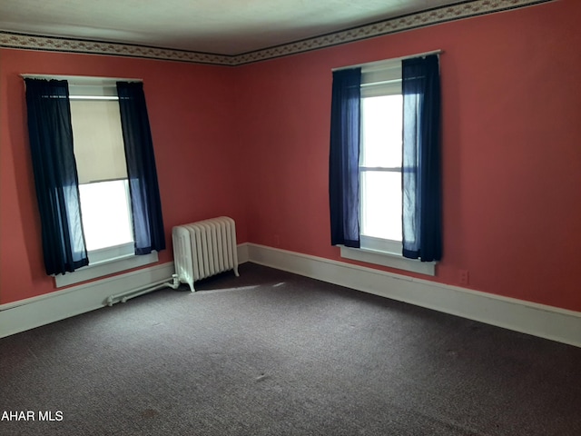 spare room featuring carpet, radiator heating unit, and baseboards