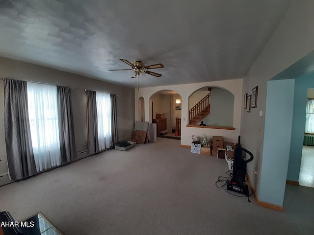 interior space with arched walkways, ceiling fan, carpet flooring, and stairs