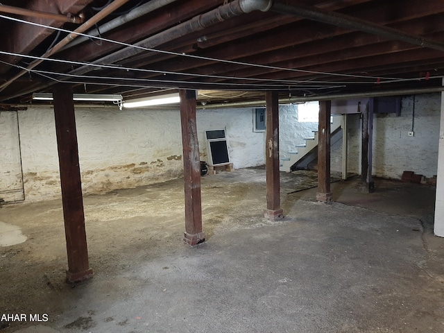 basement featuring stairs and electric panel