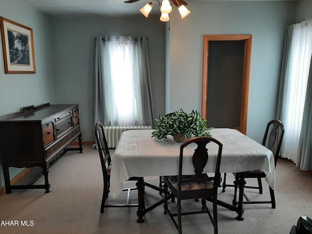 dining space with radiator, light carpet, and ceiling fan