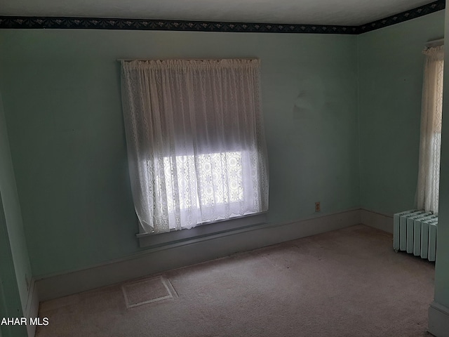 unfurnished room featuring radiator and carpet flooring