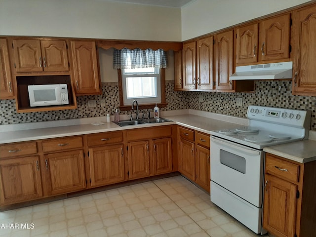 kitchen featuring white appliances, brown cabinets, light countertops, under cabinet range hood, and a sink