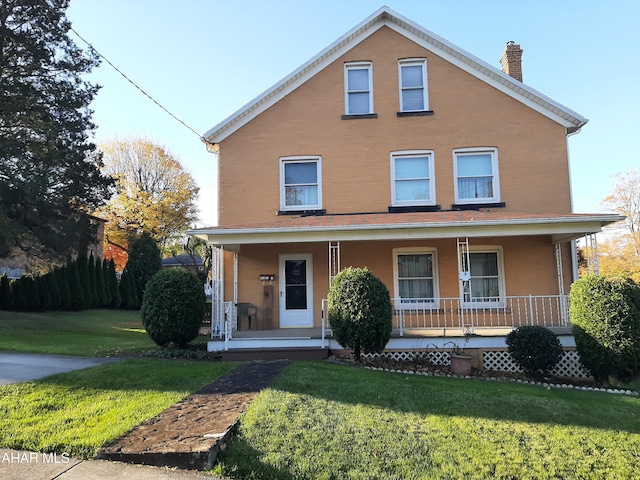 view of front of property featuring covered porch, a chimney, a front lawn, and brick siding