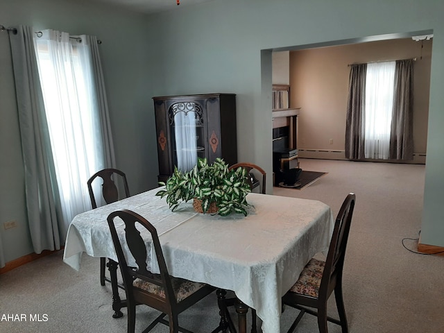 dining space with a baseboard radiator and light colored carpet