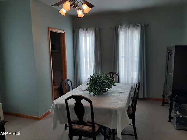 dining room featuring light carpet, a ceiling fan, and baseboards