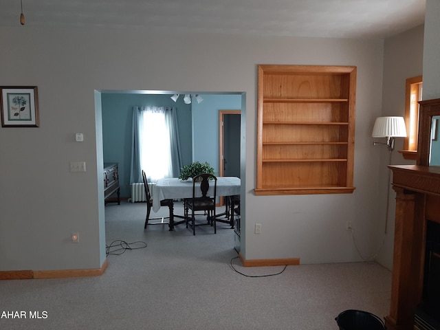 dining room with radiator, built in shelves, and baseboards