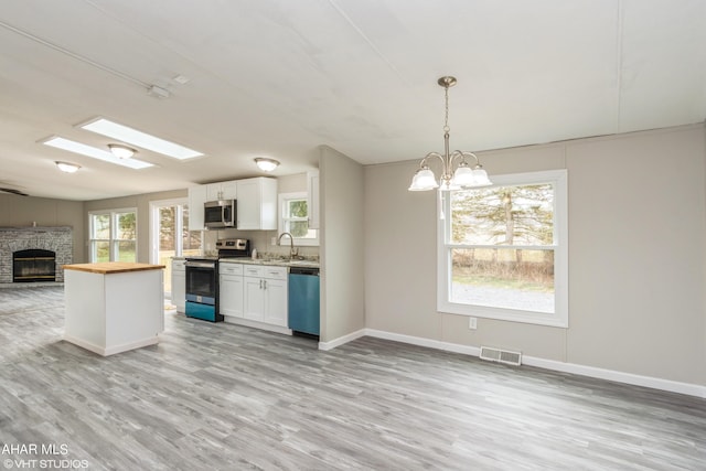 kitchen with white cabinets, decorative light fixtures, stainless steel appliances, and a wealth of natural light