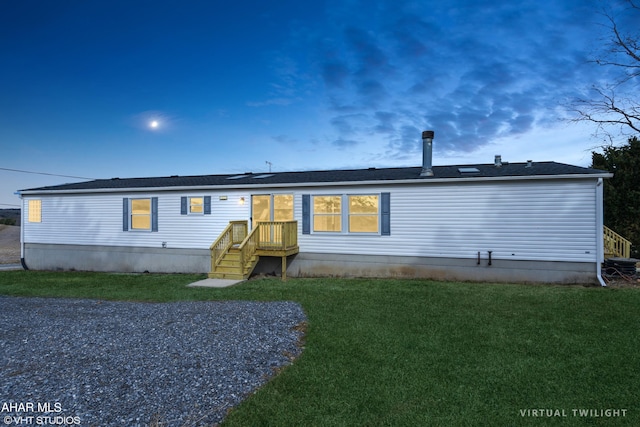 back house at dusk featuring a lawn