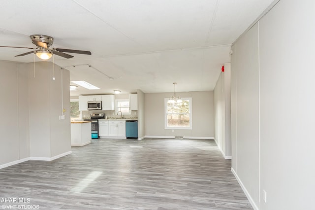 unfurnished living room with ceiling fan, light hardwood / wood-style floors, and sink