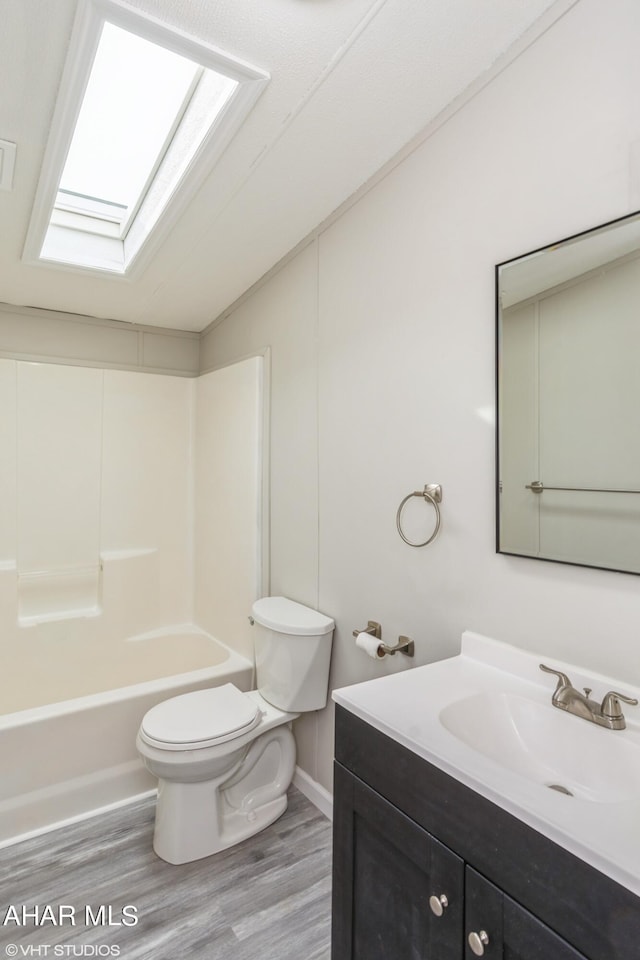 full bathroom with hardwood / wood-style flooring, vanity, toilet, and a skylight