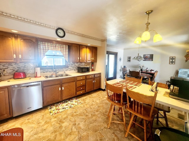 kitchen featuring tasteful backsplash, dishwasher, pendant lighting, light countertops, and a sink