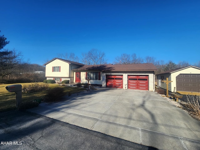 split level home featuring concrete driveway, brick siding, and a garage