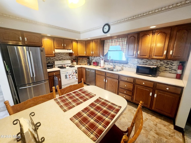 kitchen with brown cabinets, under cabinet range hood, a sink, appliances with stainless steel finishes, and light countertops