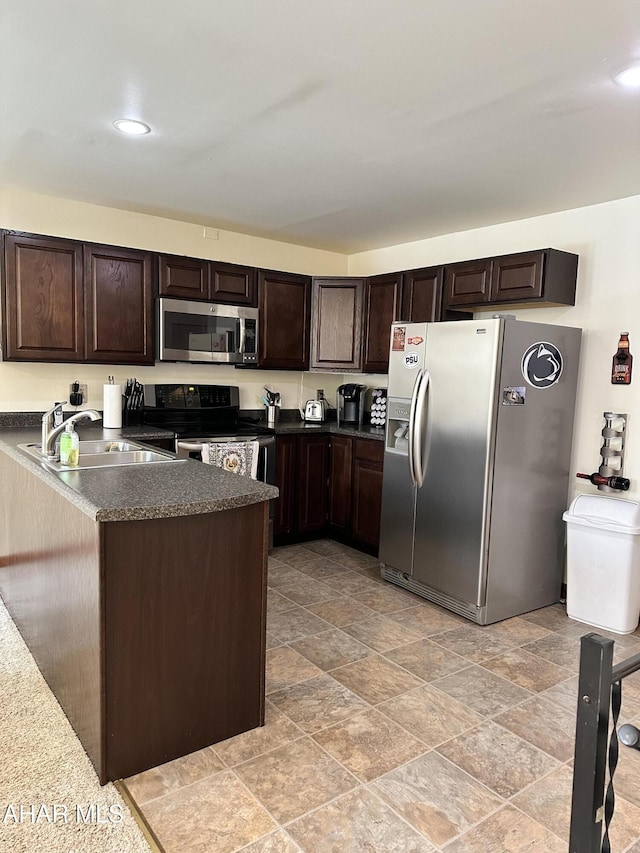 kitchen with appliances with stainless steel finishes, sink, dark brown cabinetry, and kitchen peninsula