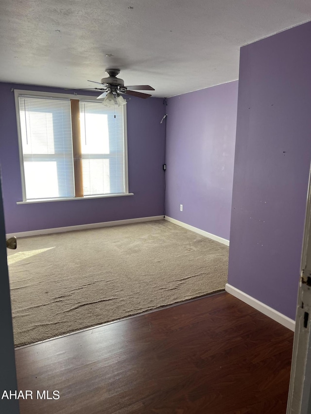 spare room with a textured ceiling, ceiling fan, and dark hardwood / wood-style floors