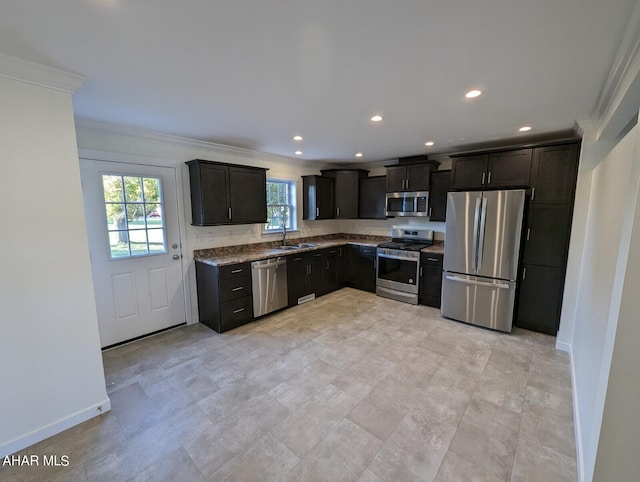 kitchen with ornamental molding, appliances with stainless steel finishes, sink, and light stone counters