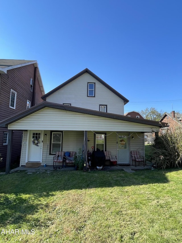 rear view of house featuring a lawn and a porch