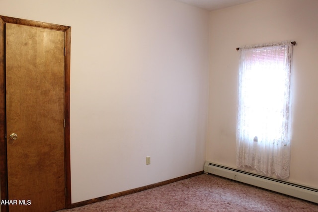 carpeted empty room with a baseboard heating unit