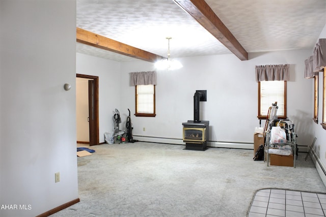 interior space featuring beam ceiling, a wood stove, light carpet, and a baseboard radiator