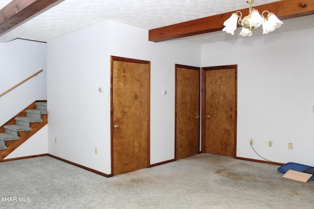 spare room featuring light carpet, beamed ceiling, a textured ceiling, and an inviting chandelier