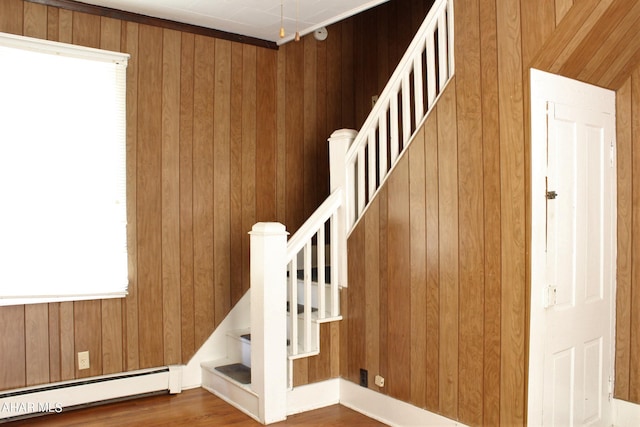 stairs featuring hardwood / wood-style flooring, wood walls, and a baseboard radiator