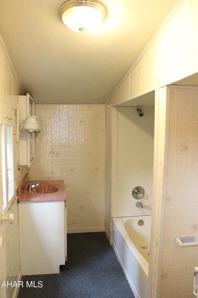 bathroom featuring vanity, bathing tub / shower combination, tile walls, and crown molding