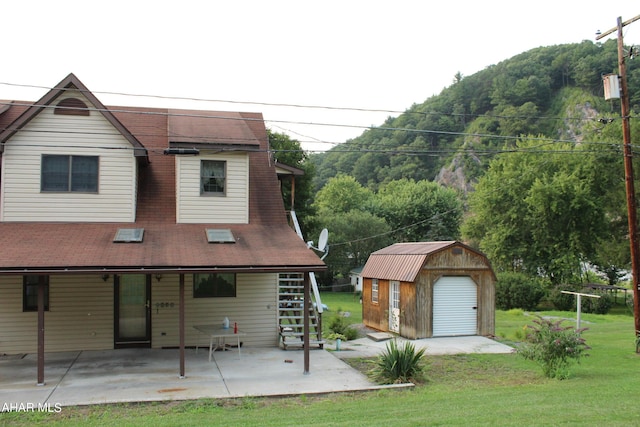 back of house with a storage shed, a yard, and a patio