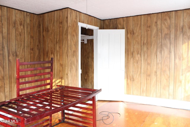 bedroom with wood-type flooring and wooden walls