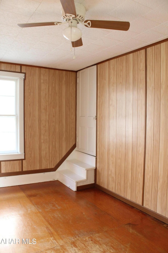 unfurnished room featuring ceiling fan and wooden walls