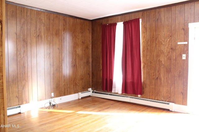 spare room featuring hardwood / wood-style floors, baseboard heating, and wood walls