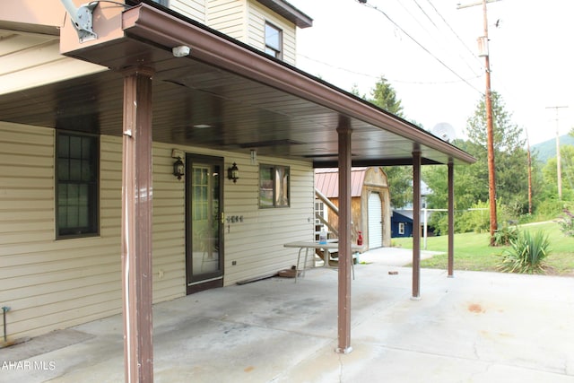 view of patio with a carport, a garage, and an outbuilding