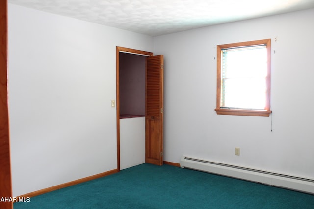 empty room featuring dark carpet, a textured ceiling, and a baseboard heating unit