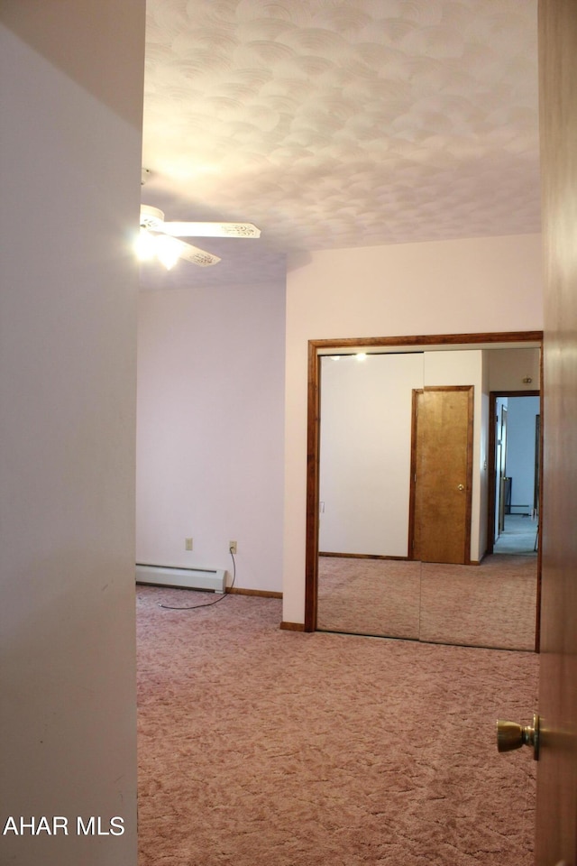 empty room featuring carpet floors, baseboard heating, and ceiling fan