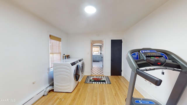 laundry area featuring hardwood / wood-style flooring, a baseboard radiator, washer and clothes dryer, and a healthy amount of sunlight