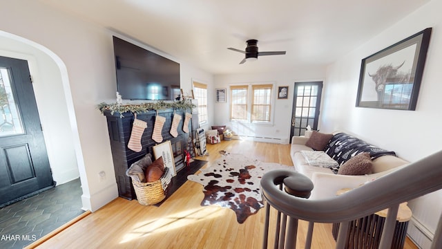 living room featuring wood-type flooring, a baseboard radiator, and ceiling fan