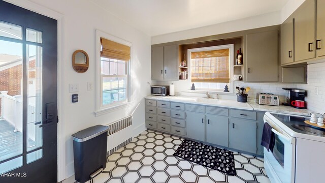 kitchen featuring decorative backsplash, plenty of natural light, electric range, and radiator heating unit