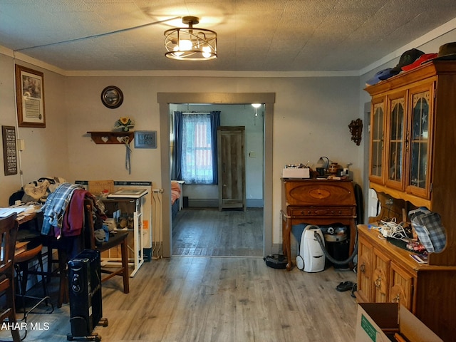 dining area with a textured ceiling, light hardwood / wood-style floors, and crown molding