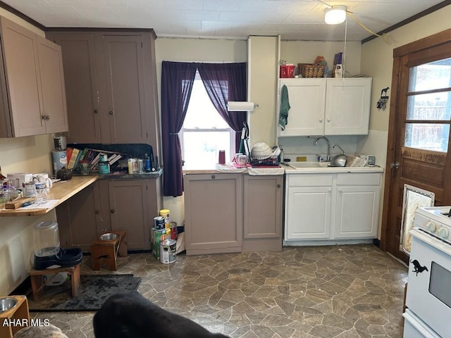 kitchen with pendant lighting, sink, white cabinetry, and white stove