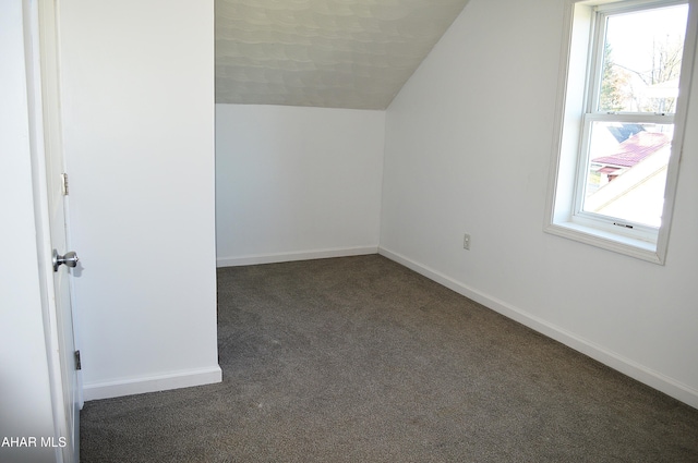 bonus room with dark carpet and lofted ceiling