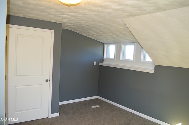 additional living space with dark colored carpet and lofted ceiling