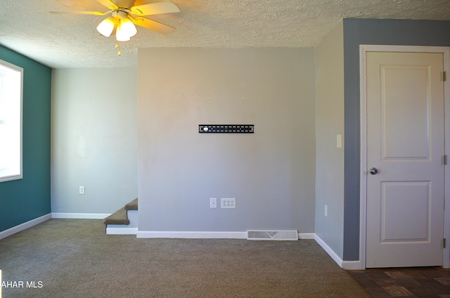 unfurnished room featuring dark colored carpet, plenty of natural light, ceiling fan, and a textured ceiling