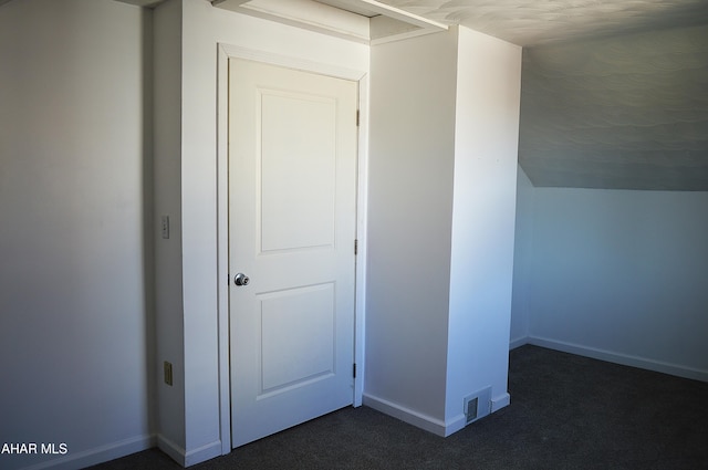 bonus room with dark carpet and vaulted ceiling