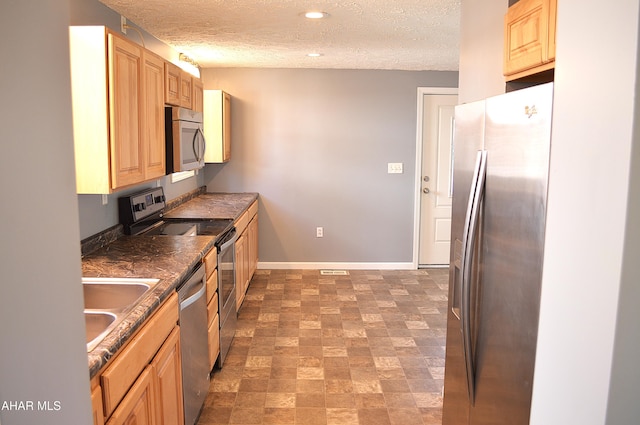 kitchen featuring a textured ceiling, light brown cabinets, sink, and appliances with stainless steel finishes