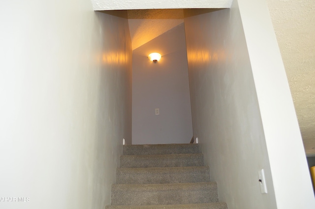 stairs featuring a textured ceiling