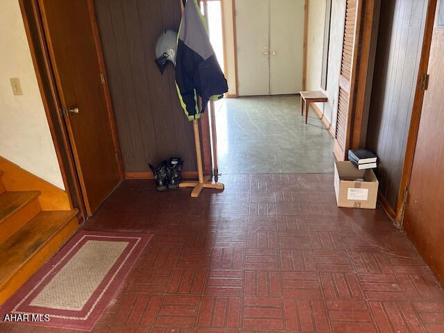 hallway with dark parquet flooring and wood walls