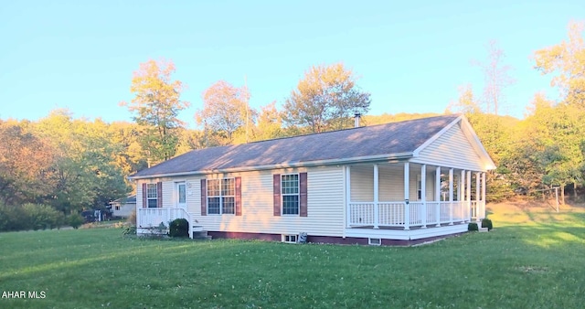 view of side of property with covered porch and a yard