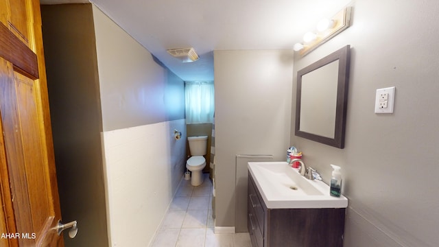 bathroom featuring toilet, vanity, tile patterned floors, and tile walls