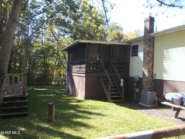 rear view of property with a sunroom, stairway, central AC unit, and a lawn