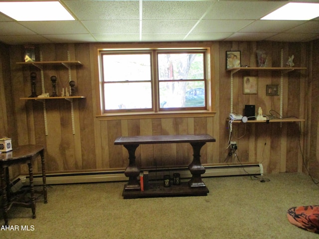 interior space with carpet floors, a paneled ceiling, and wooden walls