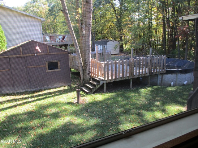 view of yard with a covered pool, an outdoor structure, and a deck